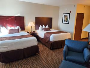 a hotel room with two beds and a chair at Cobblestone Inn & Suites Maryville in Maryville