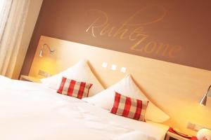 a hotel room with a bed with two red and white pillows at Klozbücher - Das Landhotel in Ellwangen