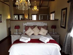 a bedroom with a large white bed with two pillows at Khumbula Lodge in Underberg