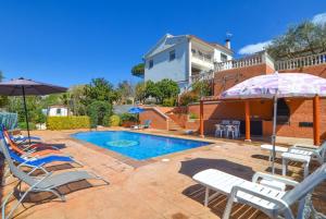 una piscina con sillas y sombrillas junto a una casa en Club Villamar - Fleming en Lloret de Mar
