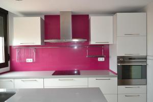 a kitchen with white cabinets and a pink wall at SAMSA House in Águilas