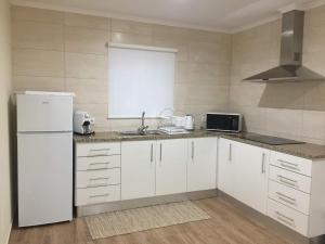 a kitchen with white cabinets and a white refrigerator at Casa do Meio in Lagoa