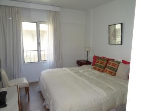 a white bedroom with a bed and a window at Arenales Apartamento in Buenos Aires