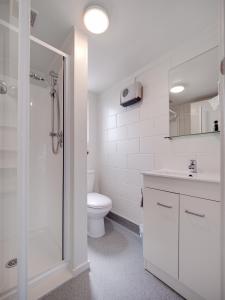 a white bathroom with a shower and a toilet at Anderson Park Motel in Cromwell