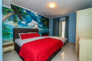 ein Schlafzimmer mit einem roten Bett und einem Palmenmilch in der Unterkunft Blue sea apartments by ArniCare in Rafailovici