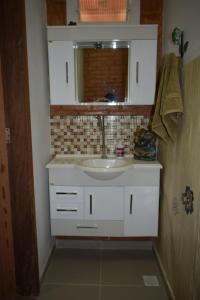 une salle de bains avec un lavabo blanc et un miroir dans l'établissement Casa do campo, à Ibitipoca 13 autres photos