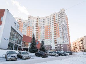 un aparcamiento con coches estacionados frente a un gran edificio en Apartment Tatiana, en Yekaterinburg