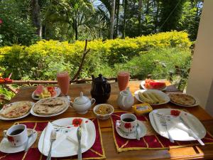 a wooden table topped with plates and cups of food at Mango Shadow Inn Ella in Ella