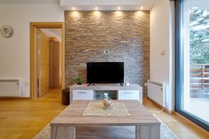 a living room with a tv on a brick wall at Apartment Imperial in Vila Pekovic Green in Zlatibor
