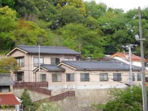ein großes beigefarbenes Haus mit schwarzem Dach in der Unterkunft ゲストハウス尾道ポポー Guesthouse Onomichi Pawpaw in Onomichi