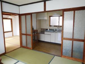 a large kitchen with white cabinets and wooden doors at ゲストハウス尾道ポポー Guesthouse Onomichi Pawpaw in Onomichi