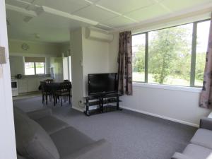 kaiwera warm cozy cottage في جور: غرفة معيشة بها أريكة وتلفزيون