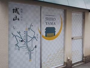 una señal en el costado de un edificio con escritura en él en Shiroyama Ryokan, en Ikuma