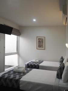 een witte kamer met 2 bedden en een raam bij Shells Apartments in Sorrento