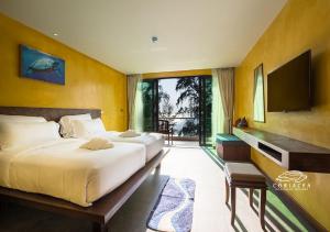 Coriacea Beachfront Boutique Phuket Resort - SHA Plus في شاطئ ماي خاو: غرفة نوم بسريرين وتلفزيون بشاشة مسطحة