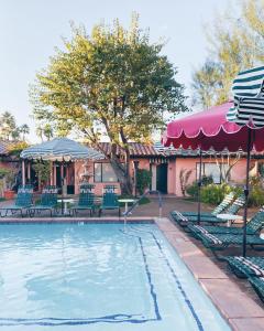 a pool with chairs and umbrellas next to a house at Les Cactus in Palm Springs