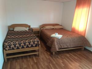 a room with two beds and a table in it at Chelitos Backpacker in Cusco