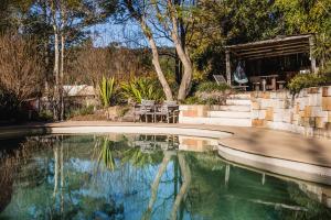 a swimming pool with a table and chairs next to a house at Capers Cottage and Barn Accommodation in Wollombi
