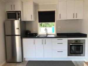 a kitchen with white cabinets and a stainless steel refrigerator at Arches Cottage in Twizel