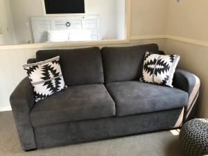 a gray couch with two pillows in a living room at Arches Cottage in Twizel