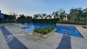 a swimming pool with blue water and plants at Lumpini seaview cha-am By Greenview in Ban Sahakham