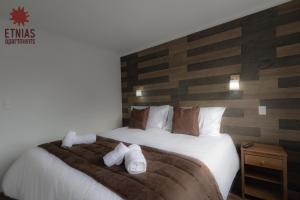 a bedroom with a large bed with white towels on it at Etnias Apartments in Puerto Natales +21 photos