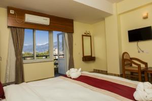 um quarto de hotel com uma cama e uma janela em Hotel Elegant em Pokhara mais 25 fotografias