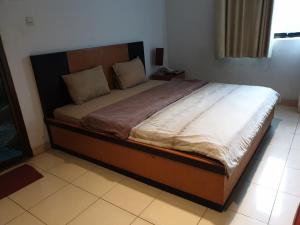 - une chambre avec un grand lit et une tête de lit en bois dans l'établissement OYO 2991 Satya Homestay, à Makassar