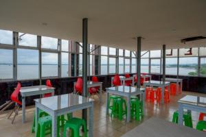 un restaurante con mesas, sillas rojas y ventanas en RedDoorz near Kendari Beach 2, en Kendari