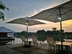 un grupo de mesas y sillas con sombrillas en River Marina Resort en Uthai Thani