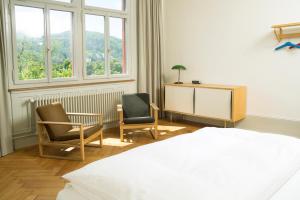 1 Schlafzimmer mit einem Bett, 2 Stühlen und einem Schreibtisch in der Unterkunft Militärkantine St. Gallen in St. Gallen