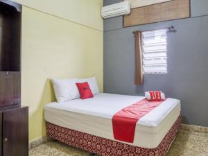 a small bedroom with a bed with red pillows at RedDoorz Syariah @ Lempuyangan in Yogyakarta