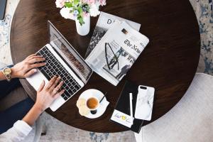 een vrouw aan een tafel met een laptop en een kopje koffie bij Leonardo Boutique Hotel Tel Aviv in Tel Aviv