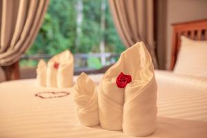 two white wedding shoes with a red rose on a bed at Luxury Camp@Green Jungle Park in Luang Prabang