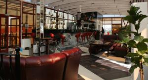 a room with a bar with red chairs and tables at Ambaritsa Hotel in Gorna Oryakhovitsa