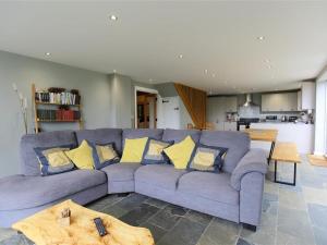 a living room with a blue couch with yellow pillows at The Cottage in Saint Briavels