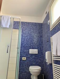 W wyłożonej niebieskimi kafelkami łazience znajduje się toaleta i prysznic. w obiekcie Hotel Riverside w mieście Modena