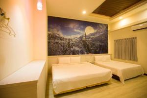 two beds in a room with a painting on the wall at Anshun Hotel in Taichung