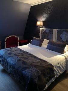 a bedroom with a large bed with a blue and white comforter at Villa Augeval Hôtel de charme & Spa in Deauville
