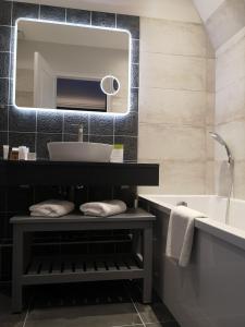 a bathroom with a sink and a tub and a mirror at Villa Augeval Hôtel de charme & Spa in Deauville