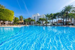 ein großer Pool mit Palmen und Gebäuden in der Unterkunft Marins Playa in Cala Millor