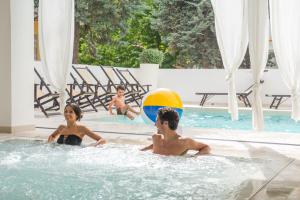 two children playing in a swimming pool with a beach ball at Hotel Tiffany & Resort in Cesenatico