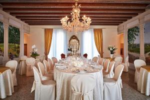 uma sala de jantar com uma mesa e cadeiras e um lustre em Villa Maria Vittoria em Nervesa della Battaglia
