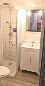 a white bathroom with a shower and a sink at A Deux Pas du Courant in Mimizan-Plage