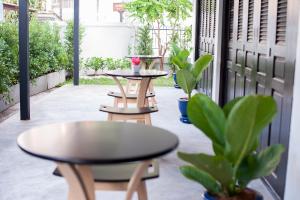 a patio with two tables and potted plants at Baan Ploy In in Chiang Mai