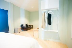 a bedroom with a white bed and a room with a chair at Baan Ploy In in Chiang Mai