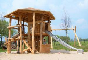 a wooden play structure with a slide in a playground at Ijsmolenhoeve in Ronse