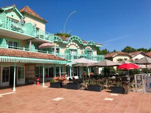 a building with a patio with tables and umbrellas at Lumineux, vue piscine, face au Golf, Lacanau Ocean in Lacanau