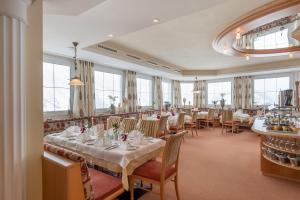 restauracja z białymi stołami, krzesłami i oknami w obiekcie Hotel Olympia w mieście Obergurgl