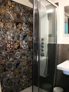y baño con ducha y pared de azulejos. en B&B La Muraglia, en Bari